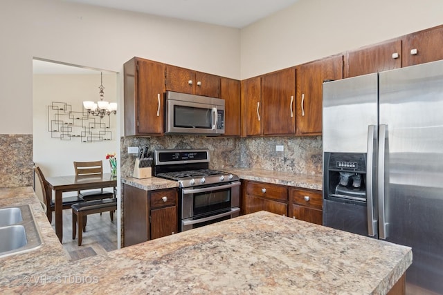 kitchen with decorative backsplash, appliances with stainless steel finishes, light countertops, and an inviting chandelier