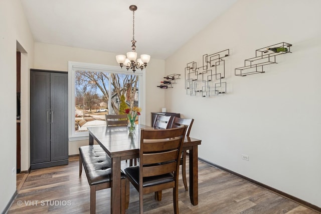 dining room with a chandelier, baseboards, and wood finished floors