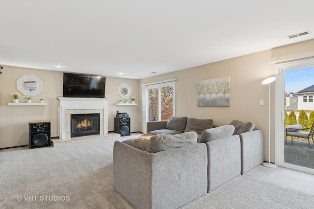 carpeted living area with visible vents and a tiled fireplace