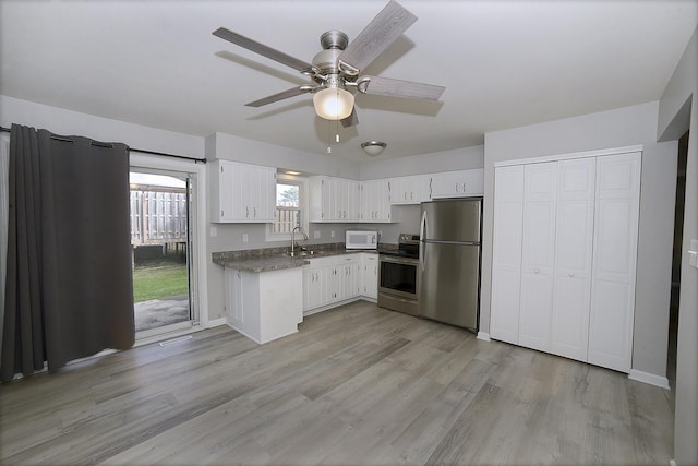 kitchen with a sink, light wood-style floors, appliances with stainless steel finishes, and white cabinetry