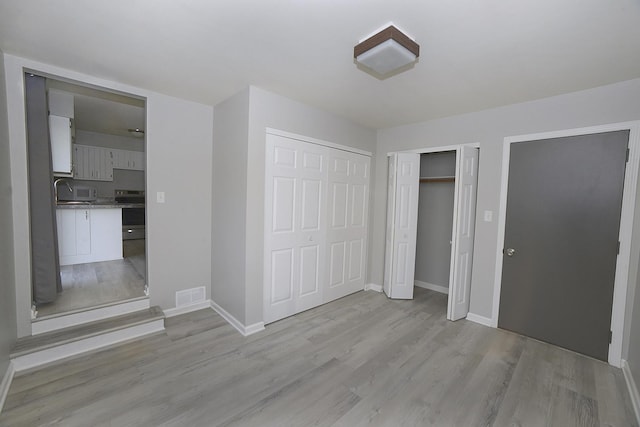 unfurnished bedroom with visible vents, baseboards, and light wood-style floors