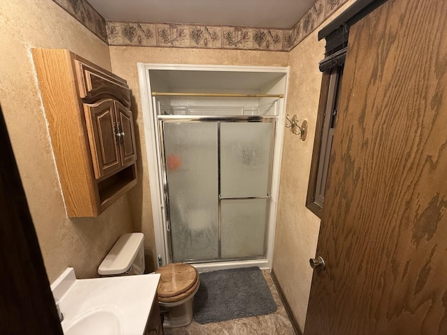 full bathroom featuring toilet, a stall shower, vanity, and a textured wall