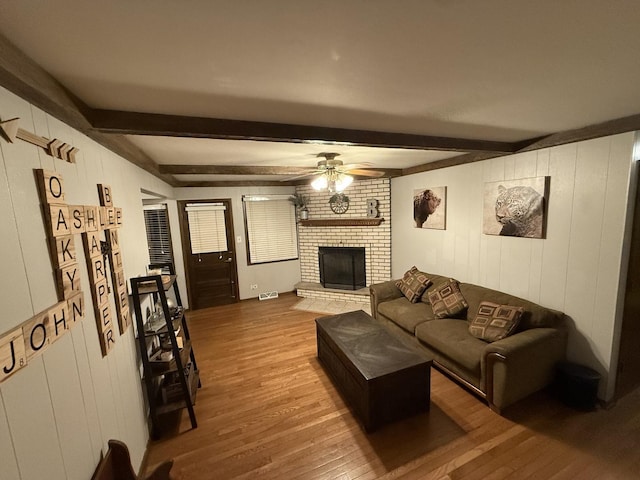 living room with visible vents, beam ceiling, wood finished floors, a fireplace, and ceiling fan