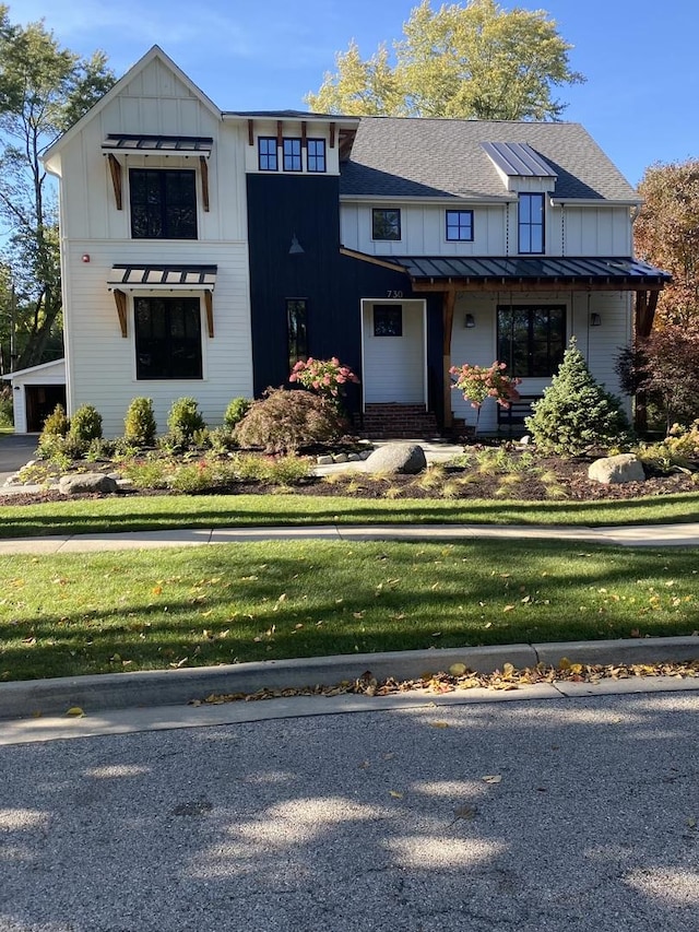 modern farmhouse style home featuring a standing seam roof, roof with shingles, metal roof, and a front lawn