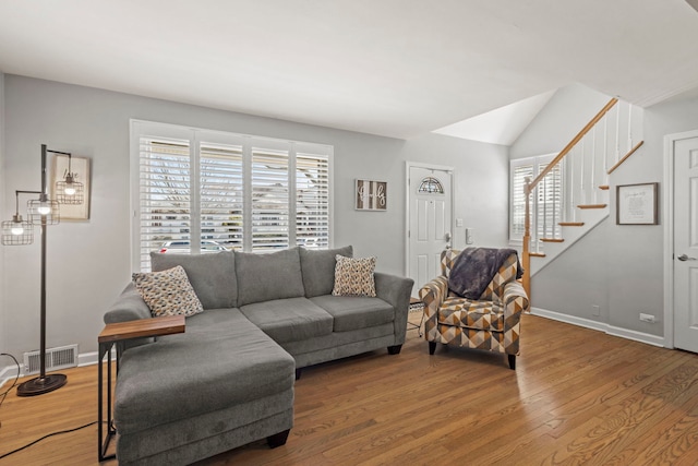 living area with stairway, wood finished floors, visible vents, and baseboards