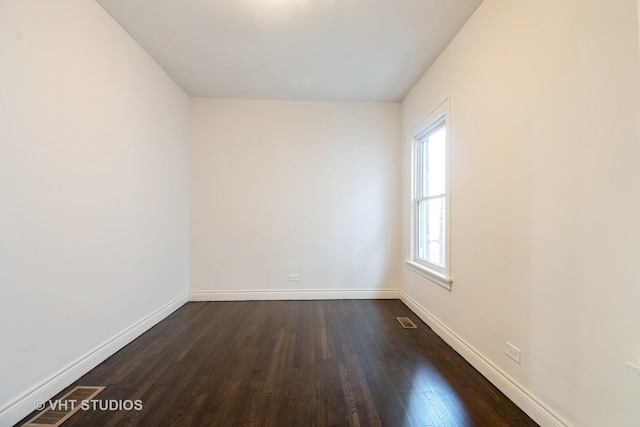 empty room with visible vents, baseboards, and dark wood-style flooring