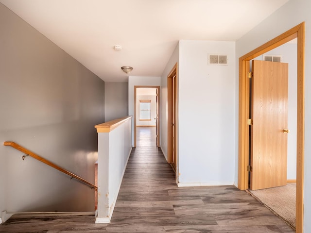 hallway featuring an upstairs landing, visible vents, baseboards, and wood finished floors