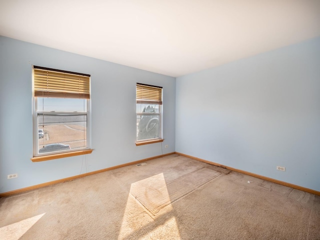 carpeted spare room featuring baseboards