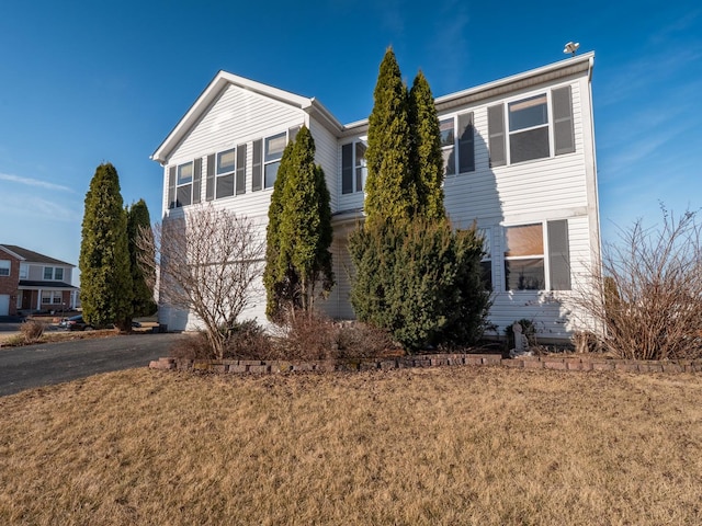 view of front of property featuring aphalt driveway and a front lawn