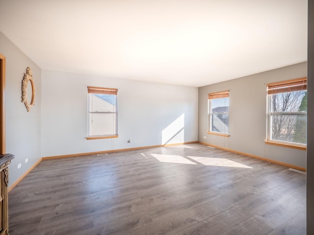 spare room with baseboards and wood finished floors