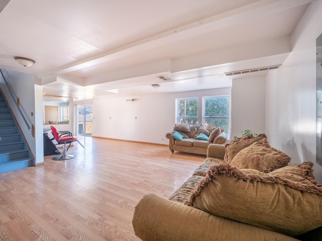 living room featuring stairway, light wood-style floors, visible vents, and baseboards