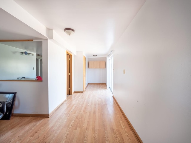 hall with baseboards and light wood finished floors