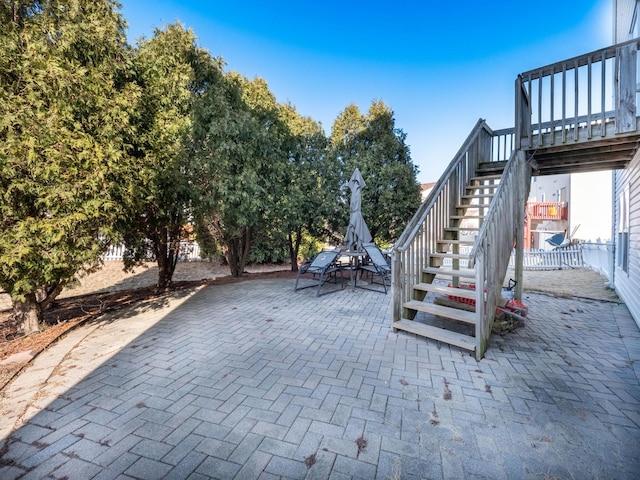 view of patio with stairway, a deck, outdoor dining space, and fence