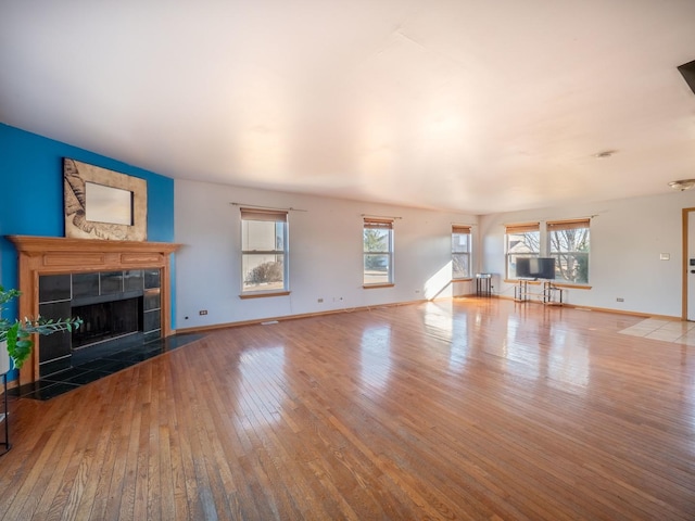 unfurnished living room featuring hardwood / wood-style floors, a fireplace, and baseboards