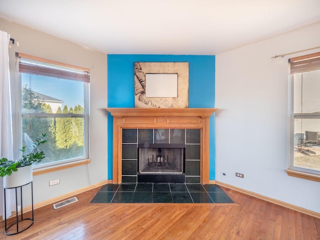 details with visible vents, baseboards, wood finished floors, and a fireplace