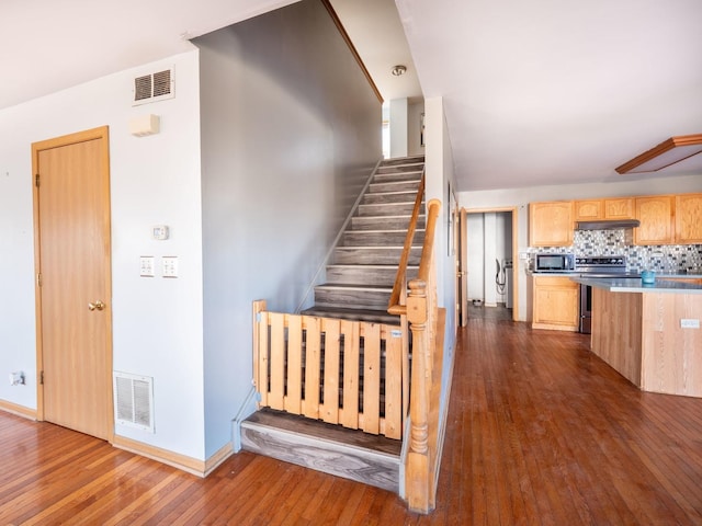 stairs featuring visible vents, baseboards, and hardwood / wood-style flooring