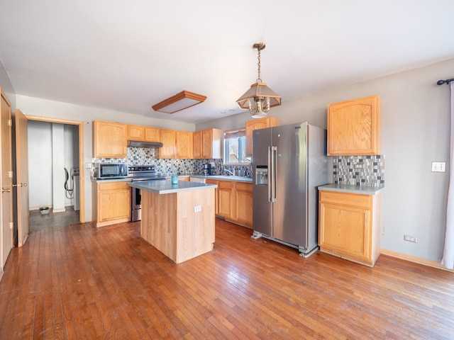 kitchen with dark wood finished floors, light brown cabinetry, under cabinet range hood, appliances with stainless steel finishes, and a center island