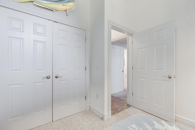 unfurnished bedroom featuring speckled floor, baseboards, and a closet