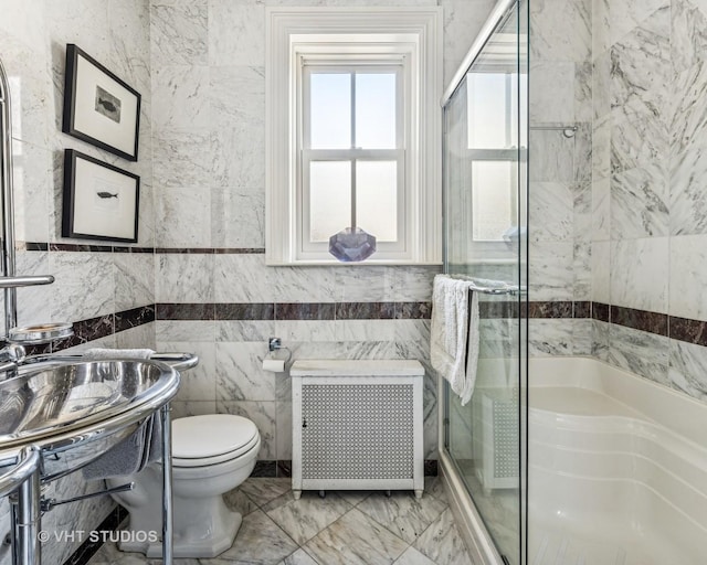 full bath featuring a shower stall, toilet, radiator heating unit, marble finish floor, and tile walls