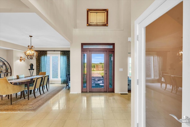 foyer entrance featuring light tile patterned floors, a notable chandelier, a high ceiling, and crown molding