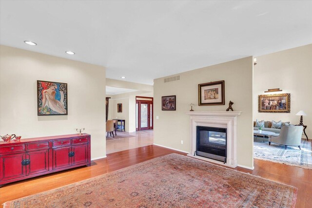 living room featuring visible vents, a multi sided fireplace, baseboards, and wood finished floors