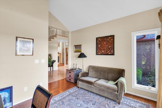 living area featuring wood finished floors, baseboards, and high vaulted ceiling