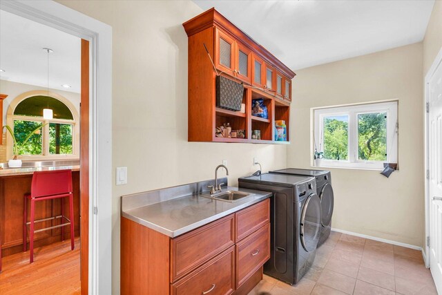 laundry room featuring baseboards, washing machine and dryer, light tile patterned flooring, cabinet space, and a sink