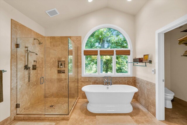 full bath featuring visible vents, a freestanding tub, a shower stall, tile walls, and toilet