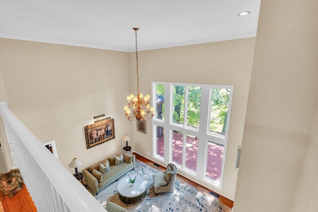 living area featuring wood finished floors, visible vents, stairs, crown molding, and a notable chandelier