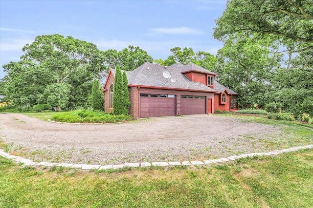 view of side of property featuring brick siding, a garage, driveway, and roof with shingles