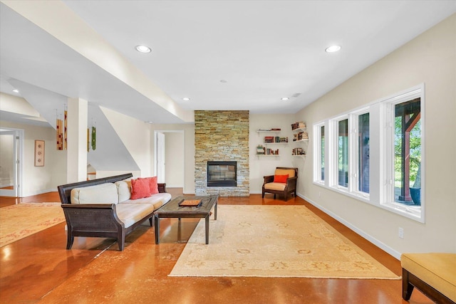 living area with a stone fireplace, recessed lighting, baseboards, and finished concrete floors