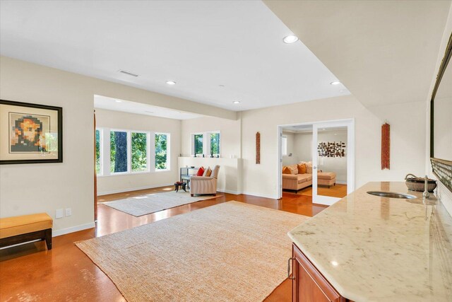 kitchen with a sink, baseboards, light stone countertops, and recessed lighting