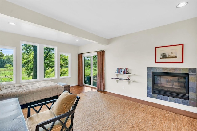 bedroom featuring access to exterior, wood finished floors, a fireplace, and recessed lighting