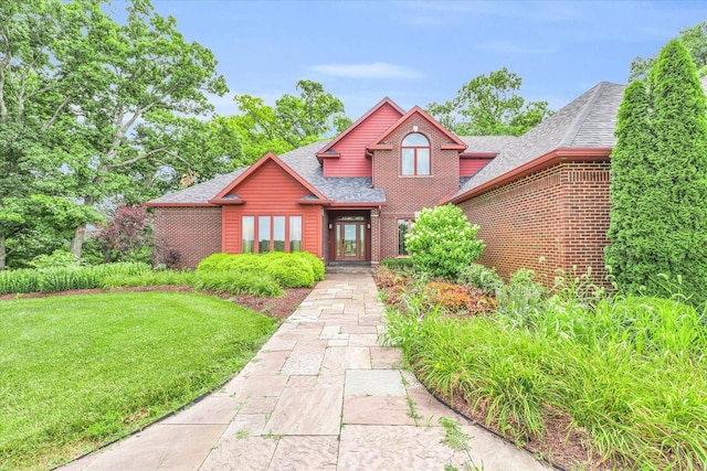 view of front of property featuring a front lawn, brick siding, and a shingled roof