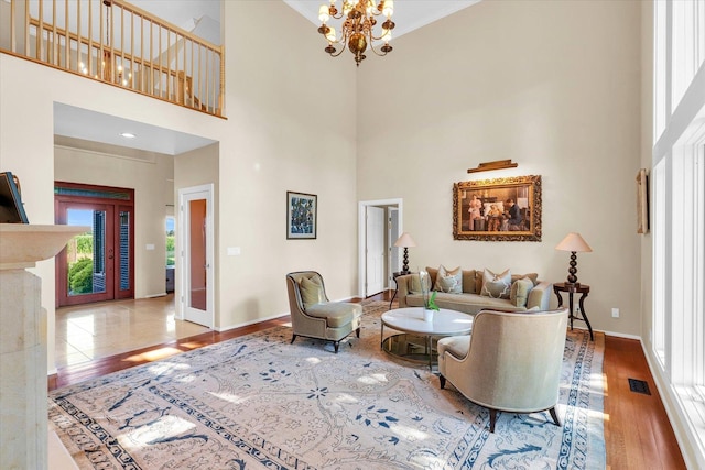 living area featuring visible vents, crown molding, baseboards, an inviting chandelier, and wood finished floors