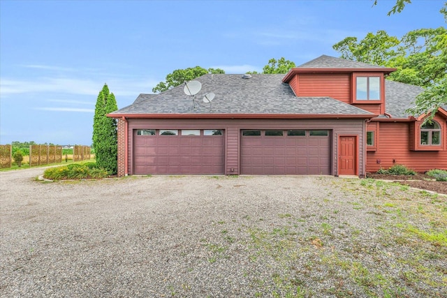 view of front facade with gravel driveway, an attached garage, and a shingled roof