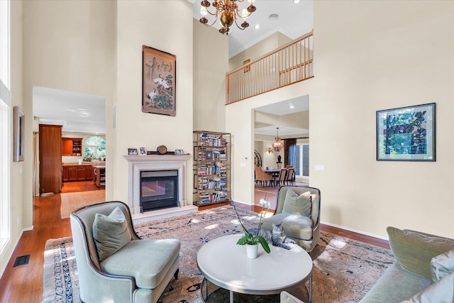 living area with a glass covered fireplace, visible vents, wood finished floors, and a chandelier