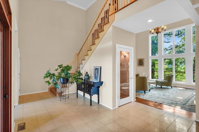 entryway featuring light tile patterned floors, baseboards, stairs, a towering ceiling, and a chandelier