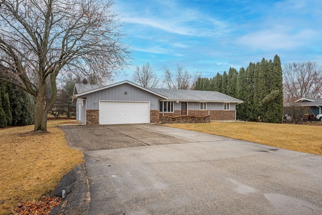 single story home featuring driveway, brick siding, an attached garage, and a front lawn