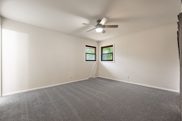 unfurnished room featuring dark colored carpet, baseboards, and ceiling fan