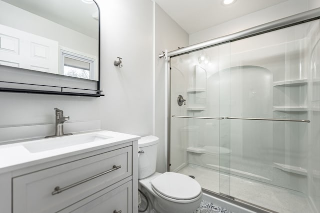 full bathroom featuring a stall shower, toilet, and vanity