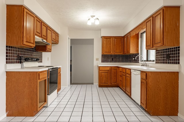 kitchen with under cabinet range hood, white appliances, brown cabinetry, and a sink