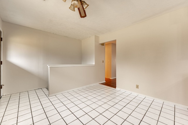 spare room with light tile patterned floors, a ceiling fan, and baseboards