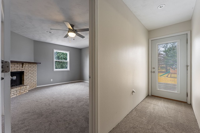 interior space featuring baseboards, a brick fireplace, ceiling fan, and carpet flooring