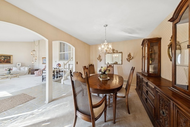 dining area featuring arched walkways, an inviting chandelier, stairs, and wallpapered walls