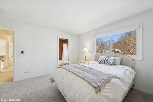 bedroom featuring carpet, arched walkways, ensuite bathroom, and baseboards