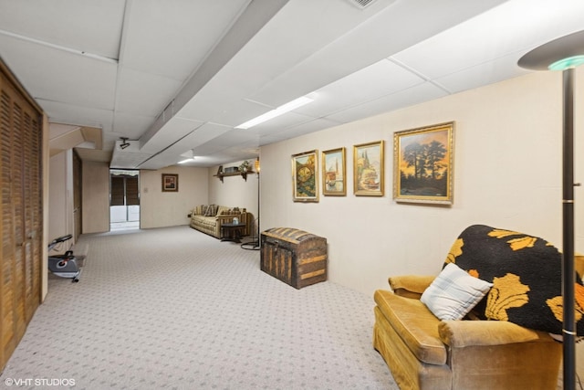 living area featuring a paneled ceiling and carpet floors