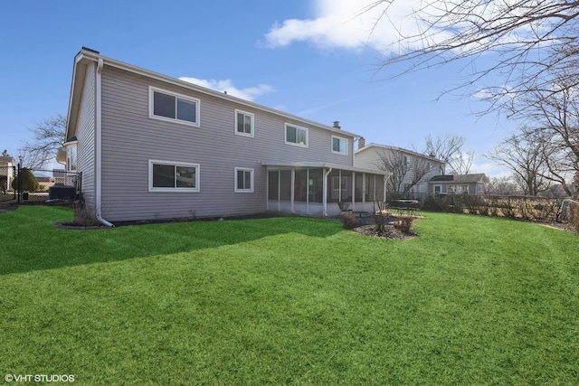 back of house featuring a lawn, a chimney, a fenced backyard, and a sunroom