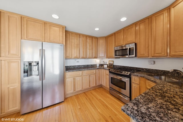 kitchen with recessed lighting, dark stone countertops, stainless steel appliances, and light wood-type flooring