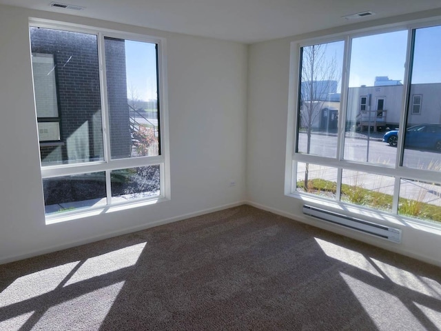 carpeted empty room with visible vents, baseboards, baseboard heating, and a healthy amount of sunlight